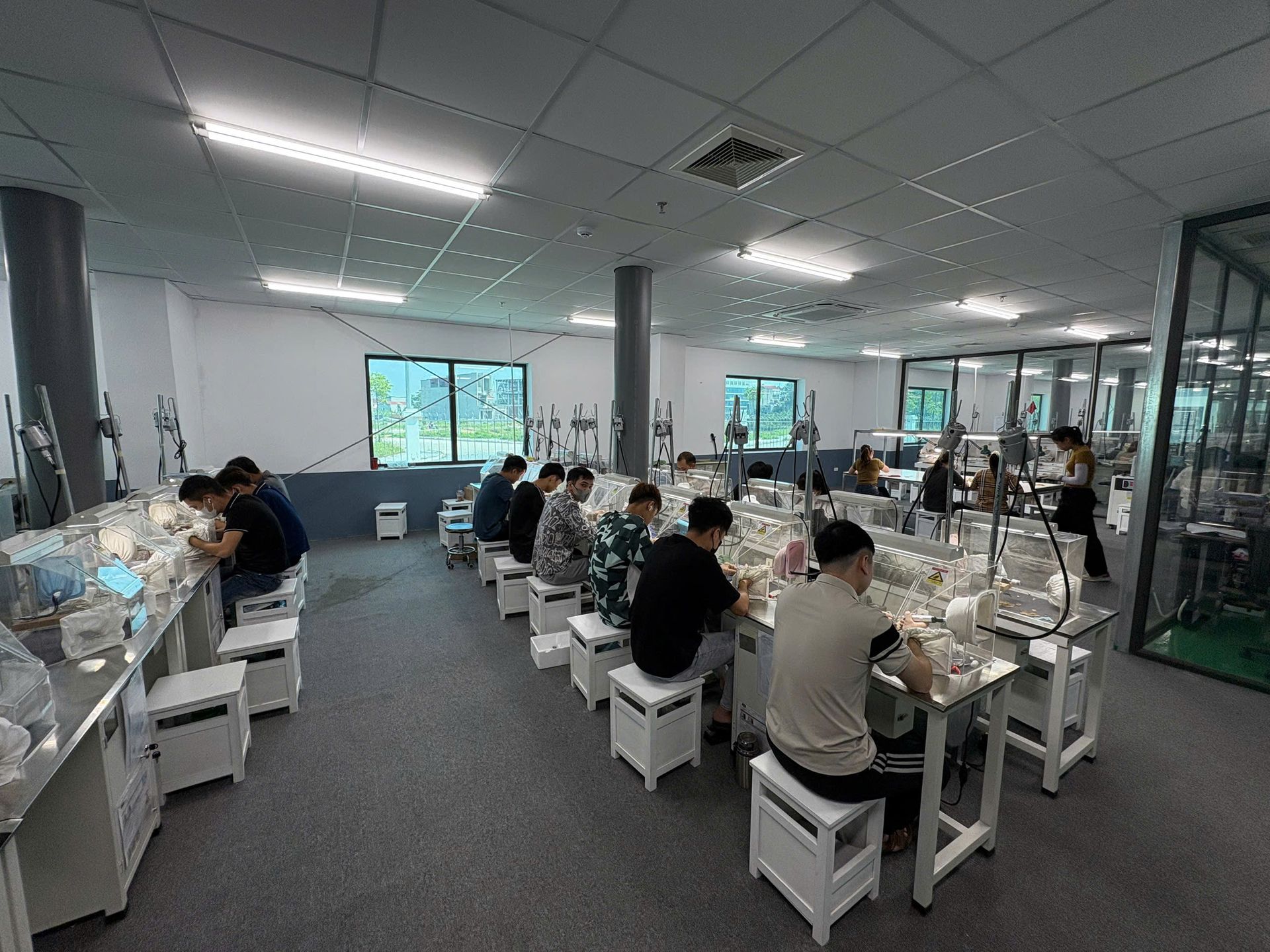 Jinyi Jewelry Factory Vietnam: Artisans at Work in Modern Production Facility | Jewelry Manufacturing Inside the modern Jinyi jewelry factory in Vietnam, skilled artisans engage in detailed jewelry production, hand-polishing custom pieces at specialized workstations.