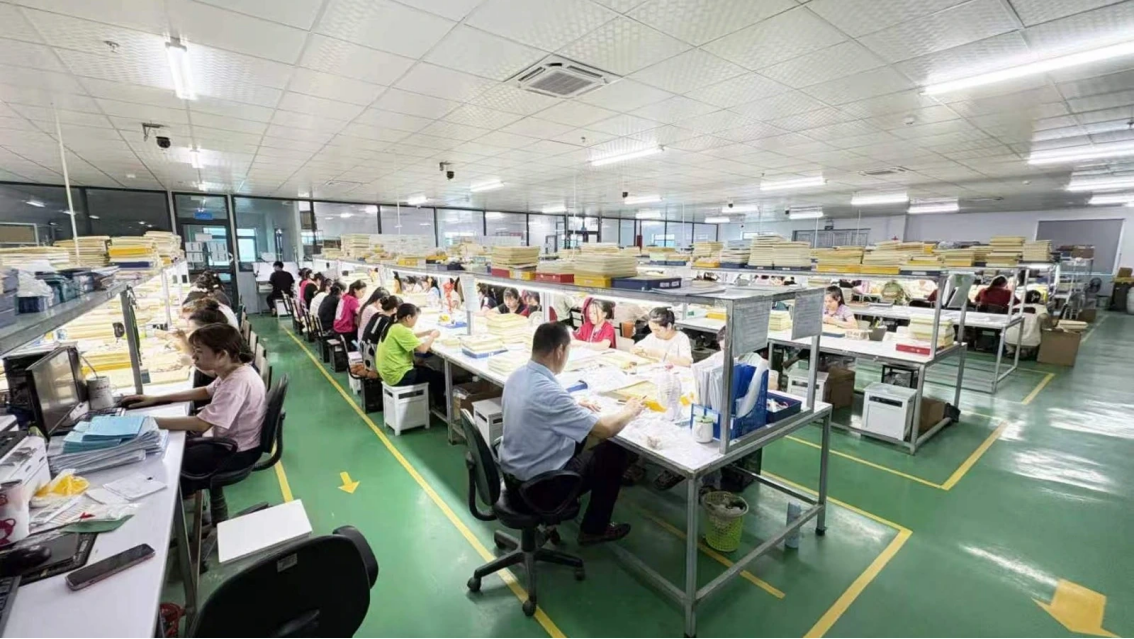 Company-supplied photograph showing JINYI Vietnam jewelry manufacturing workstations and production scale.